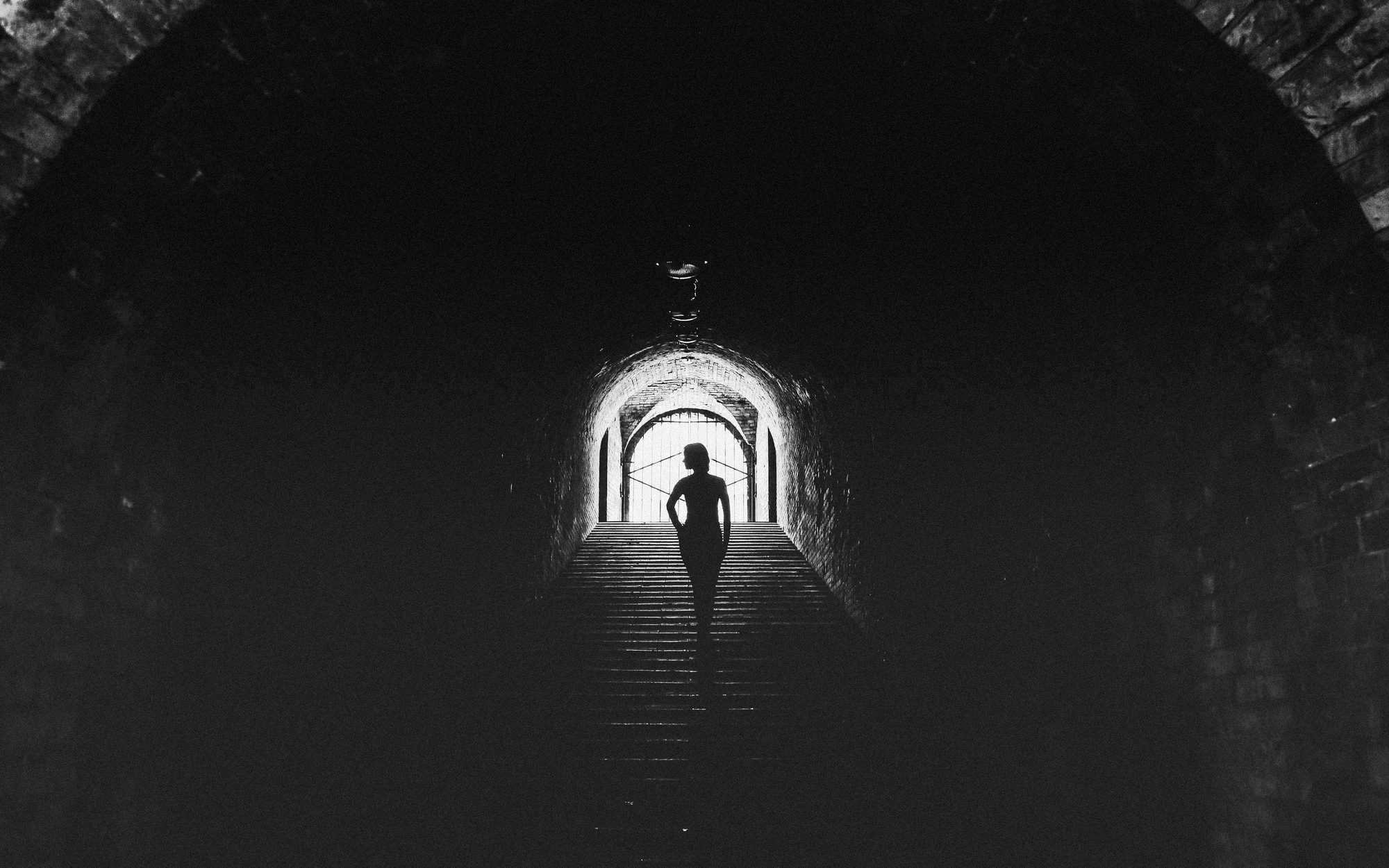A figure walking through a dark tunnel toward light